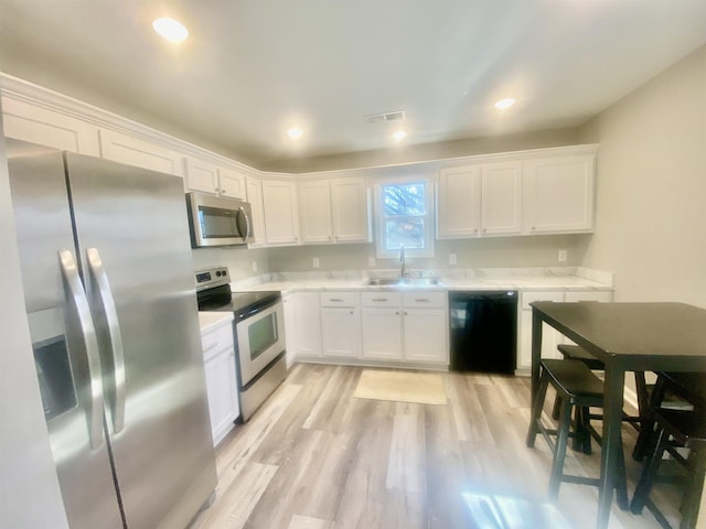 kitchen featuring white cabinets, appliances with stainless steel finishes, sink, and light hardwood / wood-style flooring