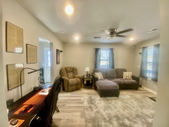 living room with ceiling fan, light wood-type flooring, and a wealth of natural light