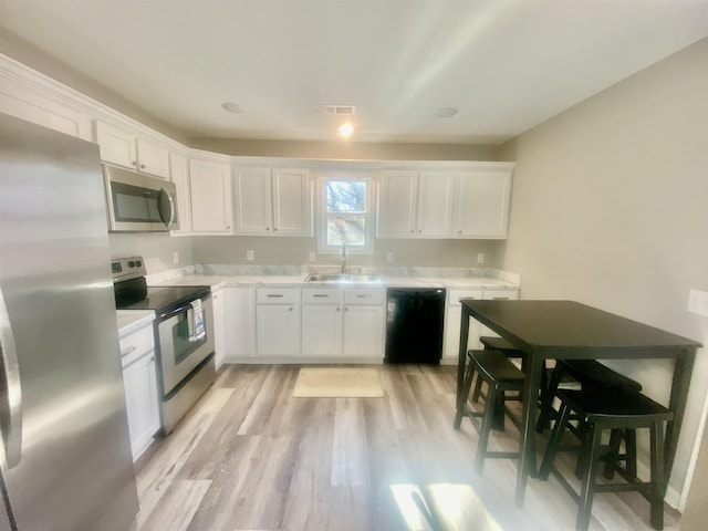 kitchen featuring light hardwood / wood-style floors, sink, white cabinetry, and stainless steel appliances