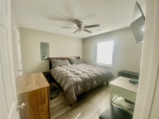 bedroom with ceiling fan, light hardwood / wood-style floors, and electric panel