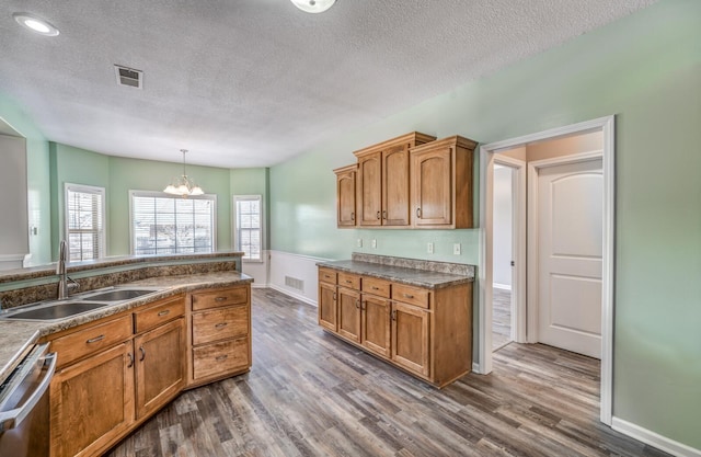 kitchen with decorative light fixtures, dark hardwood / wood-style floors, stainless steel dishwasher, sink, and a chandelier