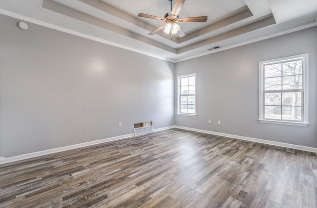 spare room featuring a raised ceiling, ornamental molding, and hardwood / wood-style floors