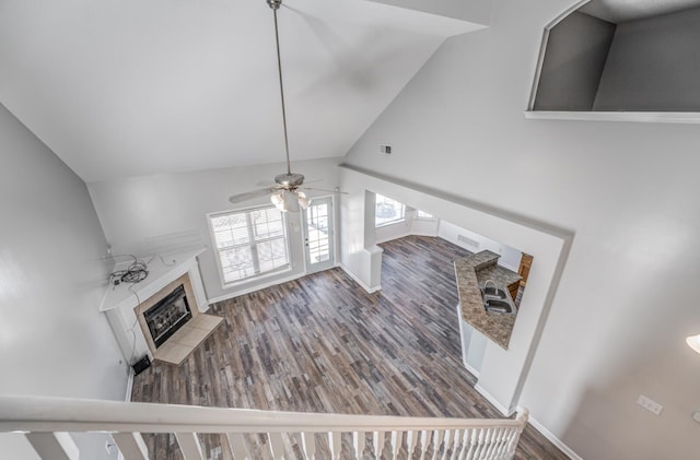 unfurnished living room featuring vaulted ceiling, ceiling fan, a fireplace, and wood-type flooring