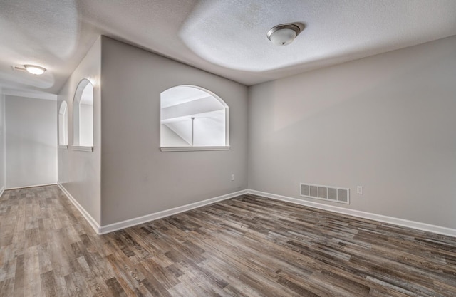 spare room featuring a textured ceiling and dark hardwood / wood-style flooring