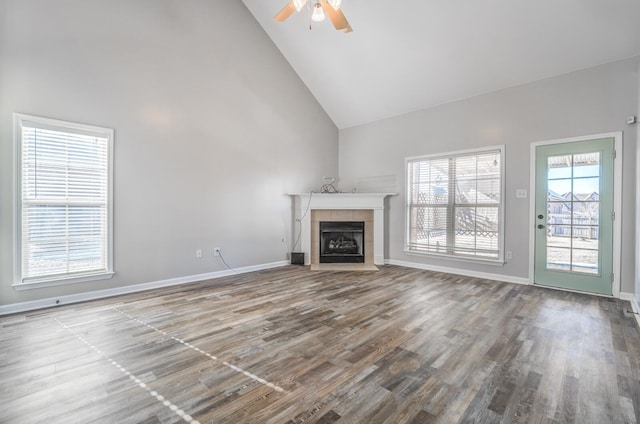 unfurnished living room featuring high vaulted ceiling, ceiling fan, hardwood / wood-style flooring, and a tiled fireplace