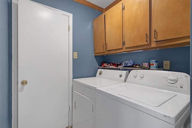 clothes washing area with washer and dryer, cabinets, and crown molding