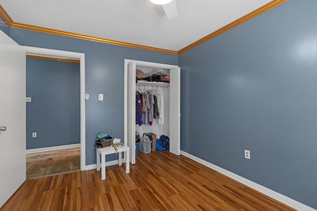 unfurnished bedroom with a closet, crown molding, hardwood / wood-style flooring, and ceiling fan