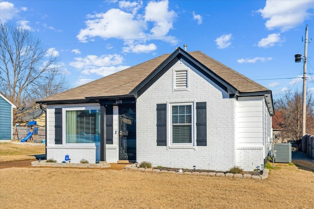 bungalow-style home with a playground, a front lawn, and central air condition unit