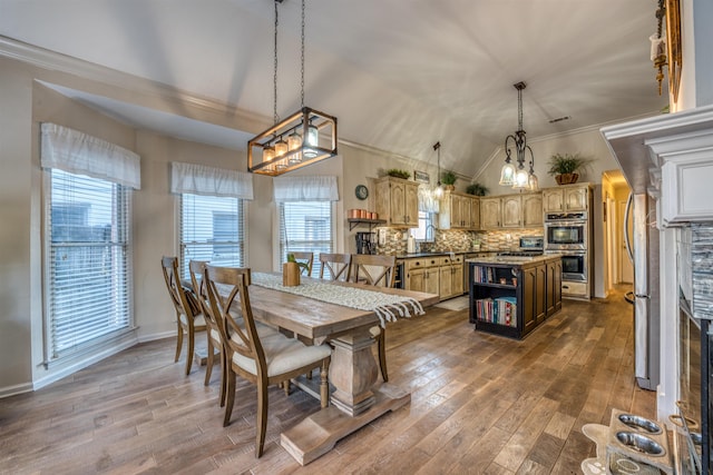 dining room with vaulted ceiling, crown molding, and dark hardwood / wood-style floors