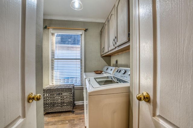 washroom with light hardwood / wood-style flooring, crown molding, washing machine and clothes dryer, and cabinets