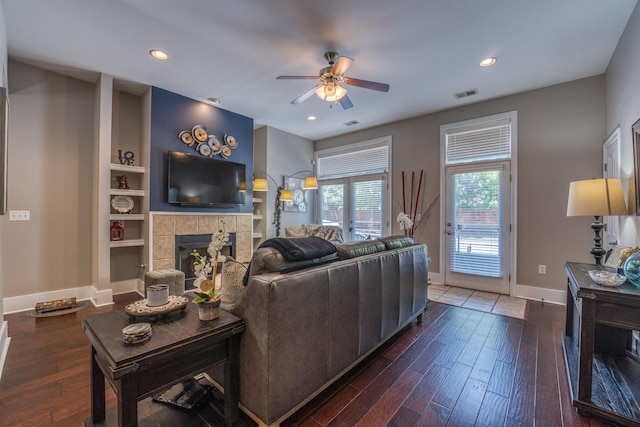 living room with ceiling fan, dark wood-type flooring, built in features, and a fireplace