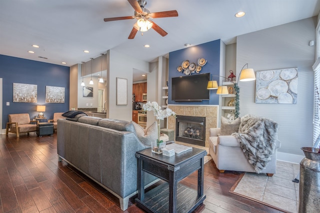 living room featuring ceiling fan, dark wood-type flooring, built in shelves, and a fireplace