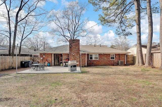 rear view of property with central AC unit, a patio area, and a yard