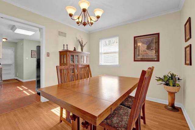 dining space featuring light hardwood / wood-style floors, ornamental molding, and an inviting chandelier