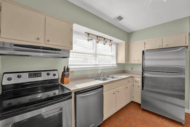 kitchen featuring dark tile patterned floors, sink, stainless steel appliances, and cream cabinets