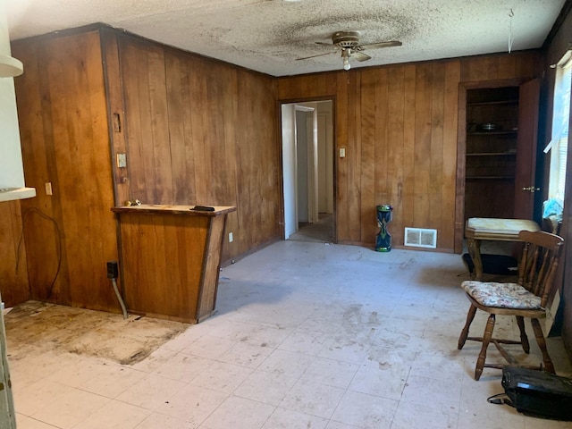 interior space featuring ceiling fan and wooden walls