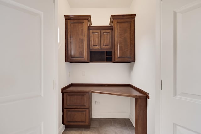 unfurnished office featuring tile patterned floors and built in desk