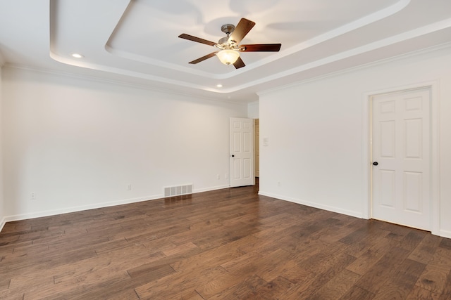 unfurnished room featuring ceiling fan, dark hardwood / wood-style floors, a tray ceiling, and ornamental molding