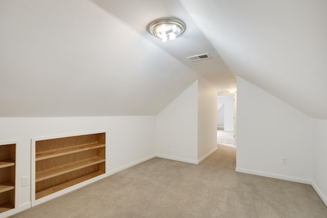 additional living space with light colored carpet, built in shelves, and lofted ceiling