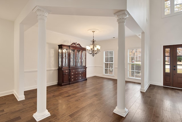 foyer featuring a notable chandelier, dark hardwood / wood-style flooring, and ornate columns