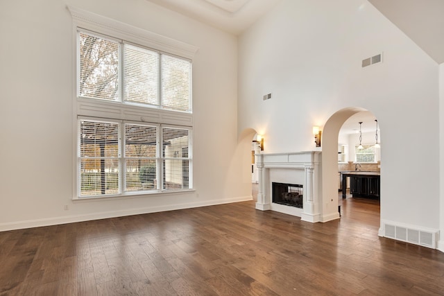 unfurnished living room featuring dark hardwood / wood-style floors, a wealth of natural light, and a high ceiling