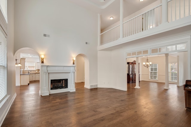 unfurnished living room featuring a notable chandelier, dark hardwood / wood-style flooring, and a towering ceiling