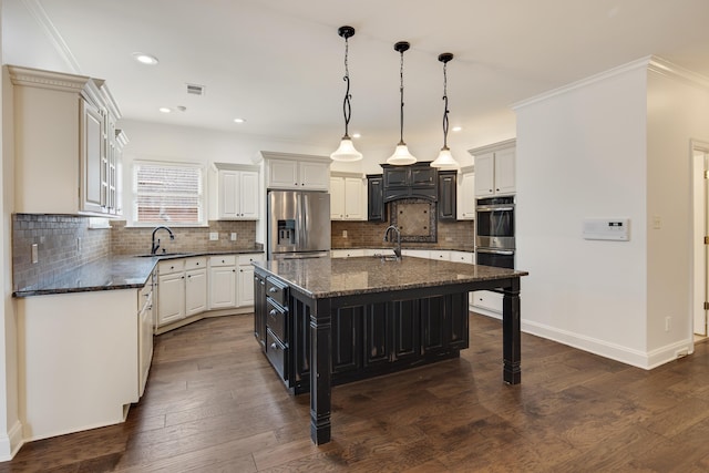 kitchen featuring a large island, appliances with stainless steel finishes, dark hardwood / wood-style flooring, pendant lighting, and sink