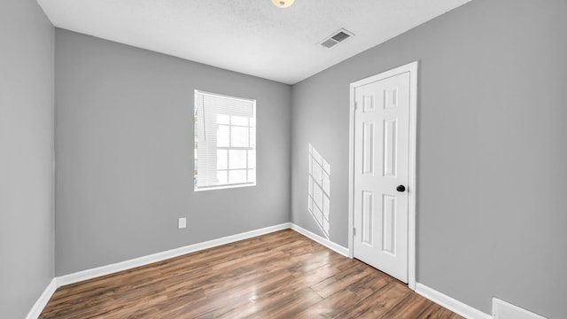 unfurnished room featuring a textured ceiling and dark wood-type flooring