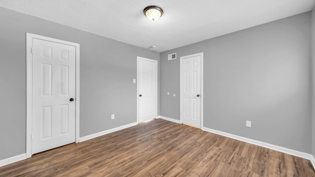 unfurnished bedroom featuring a textured ceiling and dark wood-type flooring