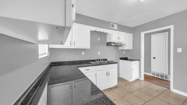 kitchen with light tile patterned floors, sink, white cabinetry, and a textured ceiling