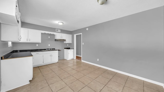 kitchen featuring sink, white cabinetry, light tile patterned floors, and a textured ceiling