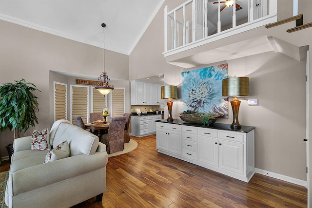 living room with high vaulted ceiling, dark hardwood / wood-style floors, ornamental molding, and ceiling fan