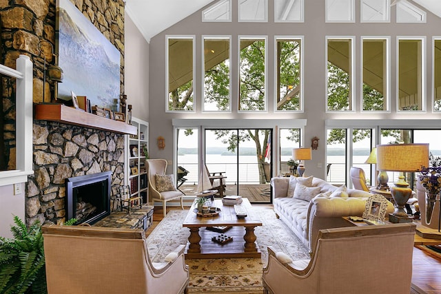 living room featuring a water view, wood-type flooring, a fireplace, and high vaulted ceiling