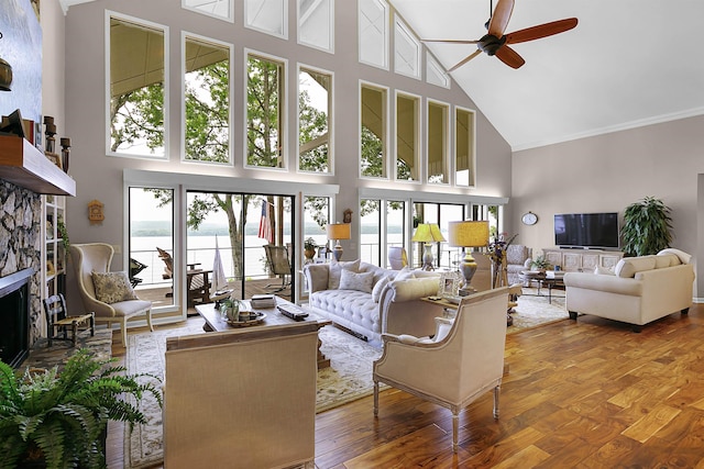 living room featuring a water view, a towering ceiling, plenty of natural light, and a fireplace