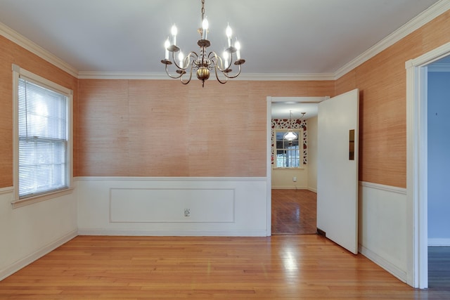 unfurnished dining area with crown molding, a chandelier, and light hardwood / wood-style floors