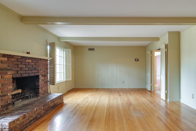 unfurnished living room with light wood-type flooring, a brick fireplace, and beam ceiling