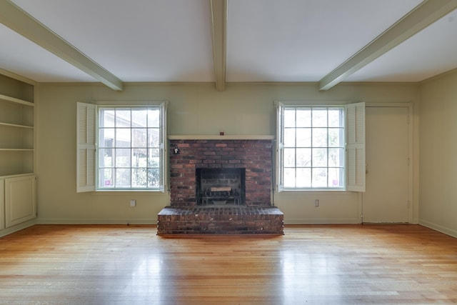 unfurnished living room featuring a wealth of natural light, light hardwood / wood-style floors, and beam ceiling