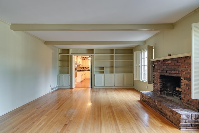 unfurnished living room with a brick fireplace, built in shelves, beam ceiling, and light wood-type flooring