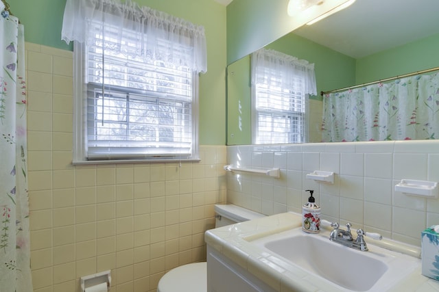 bathroom featuring curtained shower, tile walls, toilet, and vanity