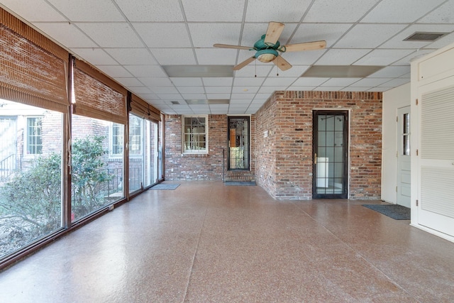 unfurnished sunroom with ceiling fan, a healthy amount of sunlight, and a paneled ceiling