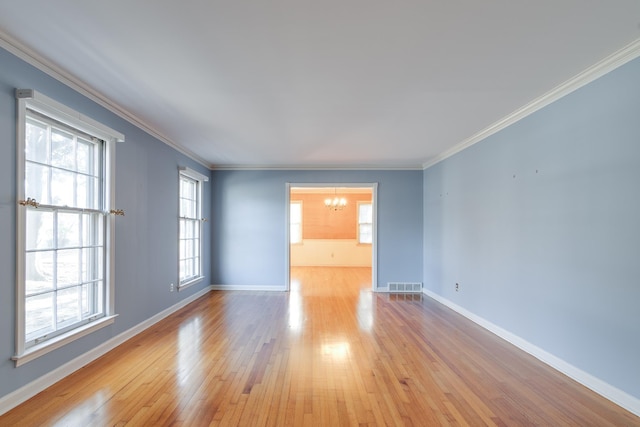 spare room featuring an inviting chandelier, crown molding, and light hardwood / wood-style flooring