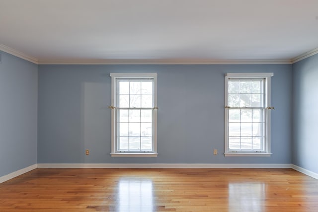 spare room featuring a wealth of natural light, light hardwood / wood-style flooring, and crown molding