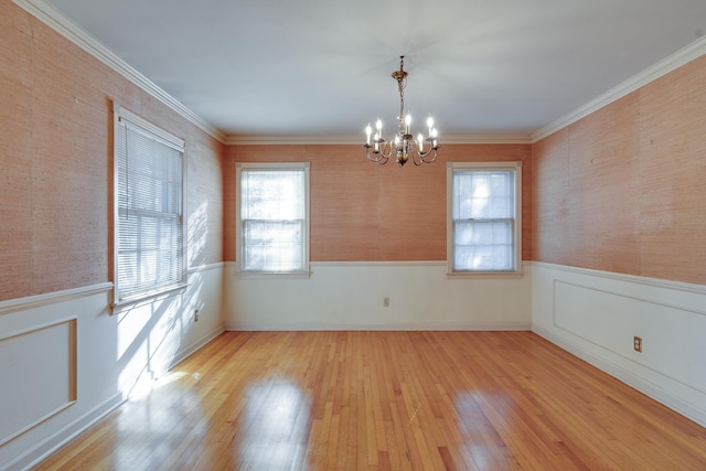 spare room featuring light wood-type flooring, an inviting chandelier, and ornamental molding