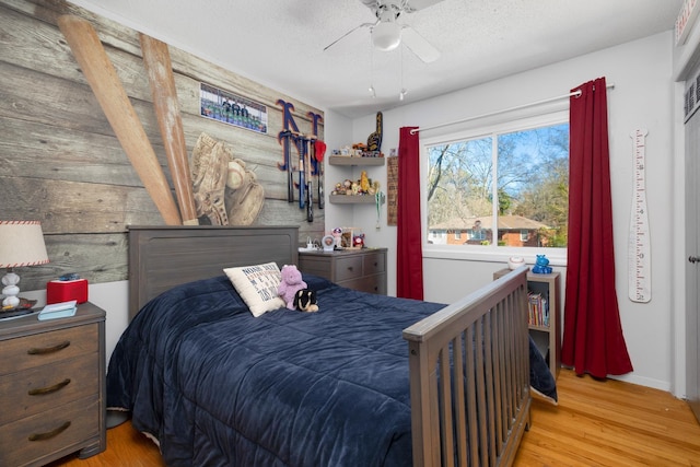 bedroom featuring ceiling fan, a textured ceiling, and light hardwood / wood-style flooring