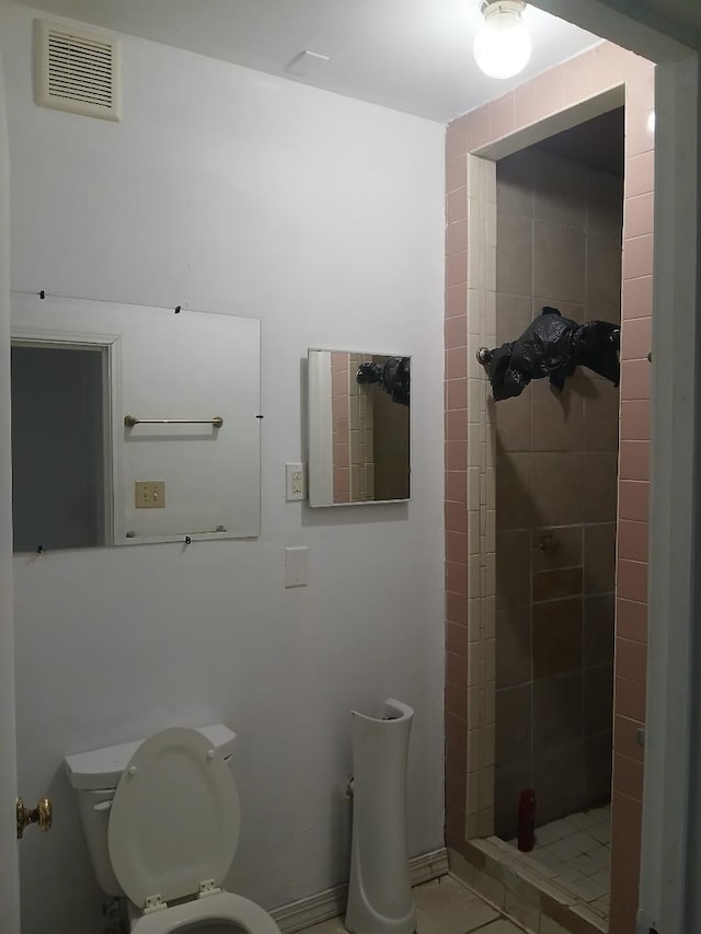 bathroom featuring tiled shower and toilet