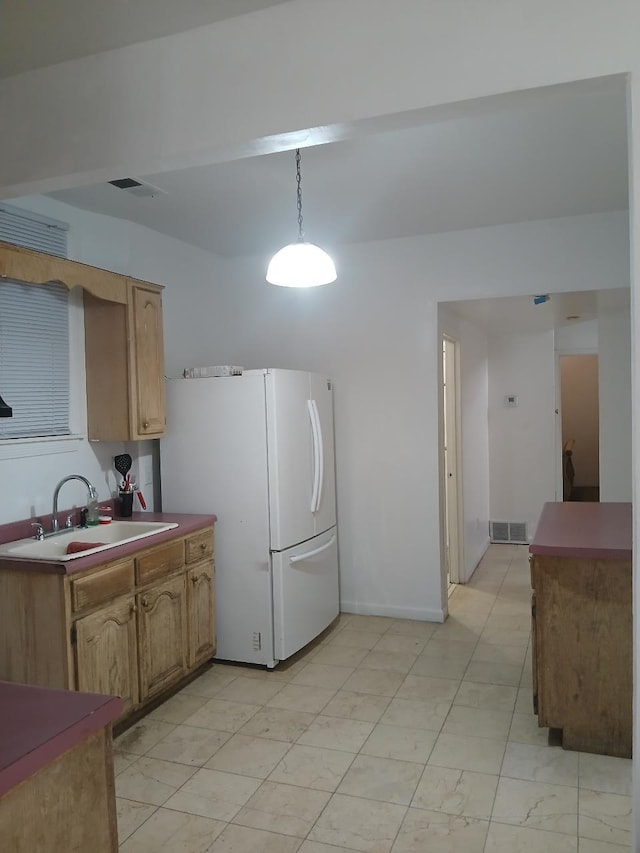 kitchen with hanging light fixtures, sink, and white fridge