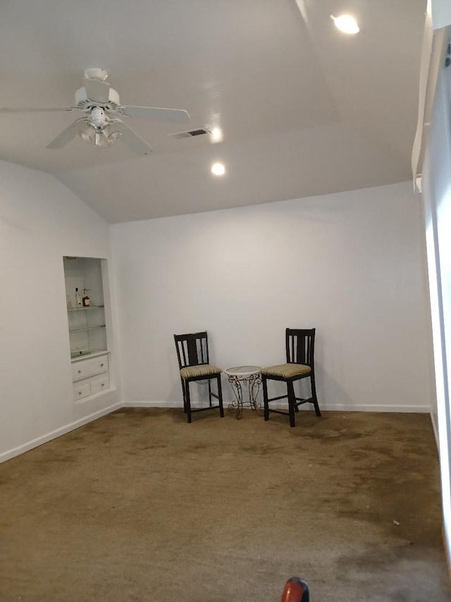 sitting room with built in shelves, ceiling fan, lofted ceiling, and dark colored carpet