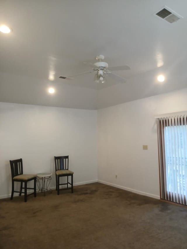 spare room featuring ceiling fan and dark colored carpet