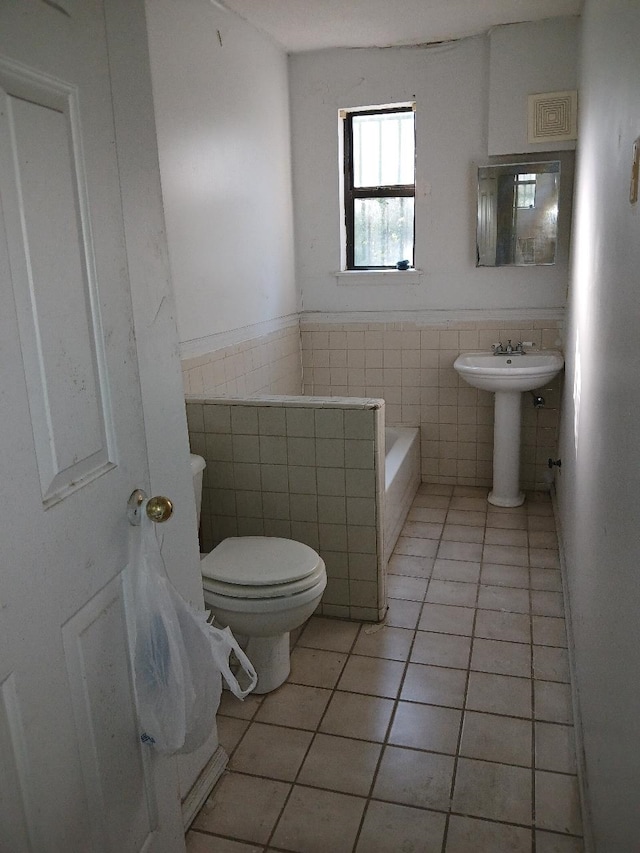 bathroom with tile patterned flooring, sink, tile walls, and toilet