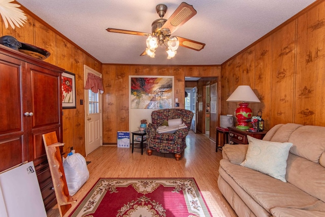 living room with light wood-type flooring, wood walls, and ornamental molding